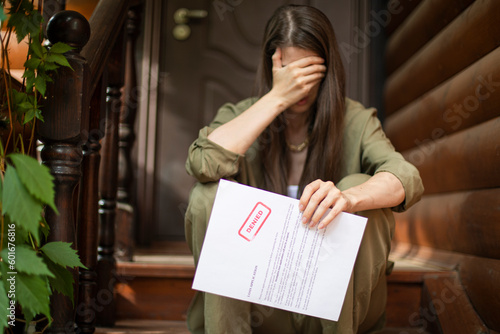 Young brunette long hair girl cries hysterically after being denied a mortgage loan. Depressive sad eviction female millenial holding rejection document copy space banner