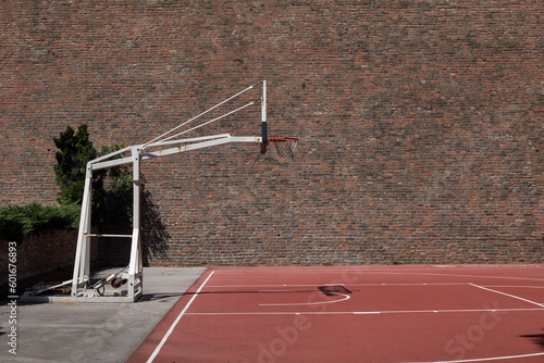 The basketball court in the park, next to the old brick wall.