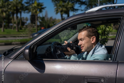 Hidden photographing. Paparazzi Concep Photographer uses his professional camera. Private detective man in car window. Mobile reporter. Photojournalist at work. Detective or investigator. © Volha