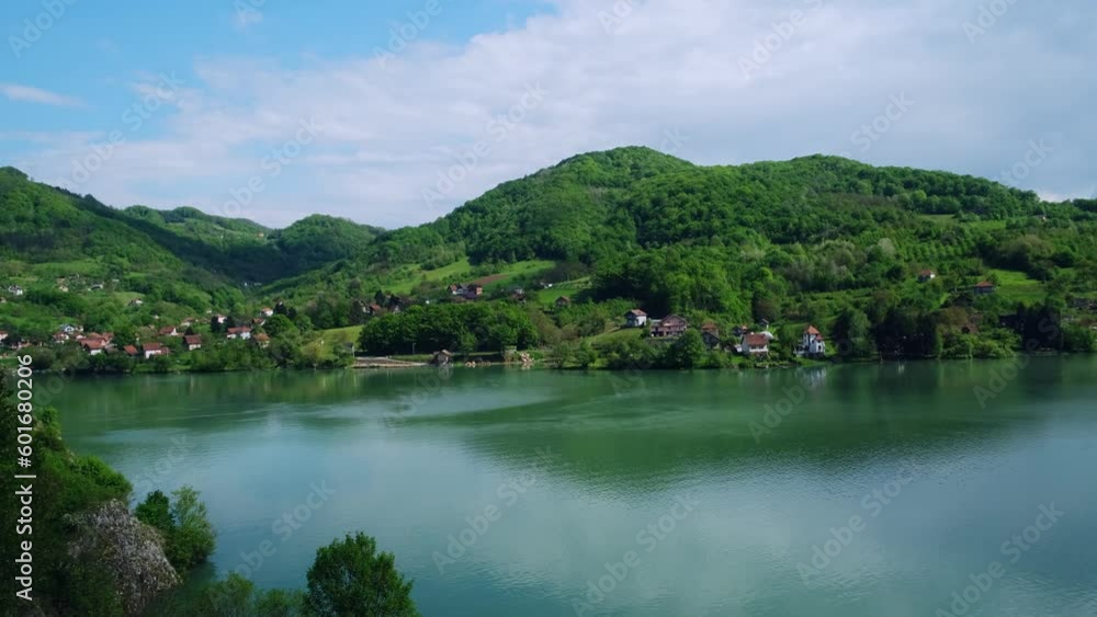 Beautiful view of mountain river and small village from the observation deck. Stunning landscape of the lake with emerald water on the background of green hills and blue sky on a sunny summer day. Beautiful view of mountain river and small village from the observation deck. Stunning landscape of the lake with emerald water on the background of green hills and blue sky on a sunny summer day.