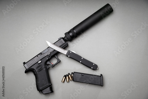 A pistol with a silencer and a folding knife.
