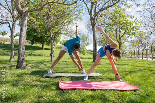 young multiethnic couple, doing flexibility exercises in the park, healthy life concept,