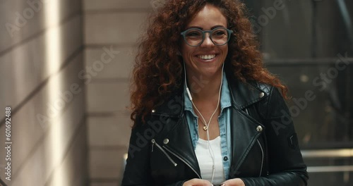 Stylish young woman smiling and listening to music on her cellphone while riding up a metro station escalator 
