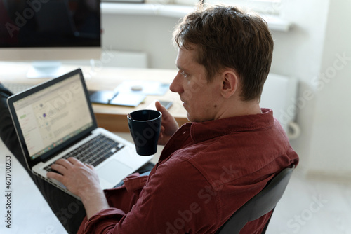 young man sitting and typing on laptop, distant work