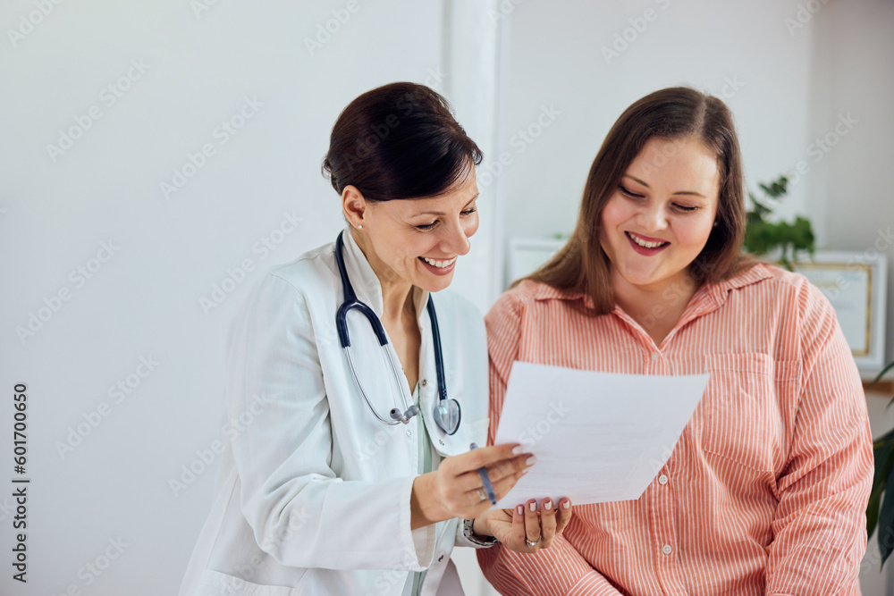 A smiling female nutritionist showing good progress results to a happy overweight patient. A smiling female nutritionist showing good progress results to a happy overweight patient.