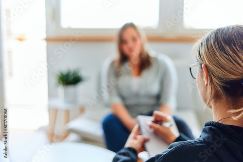 A psychotherapist taking notes during a conversation with an overweight woman.