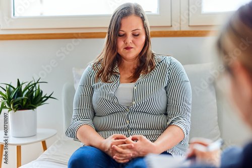 A shy overweight woman on a consulting with a psychotherapist, feeling sad. photo