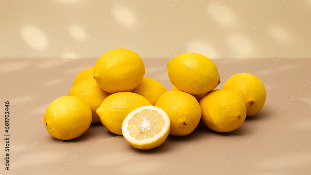 A handful of yellow ripe lemons on a beige background with a shadow pattern. A handful of yellow ripe lemons on a beige background with a shadow pattern.