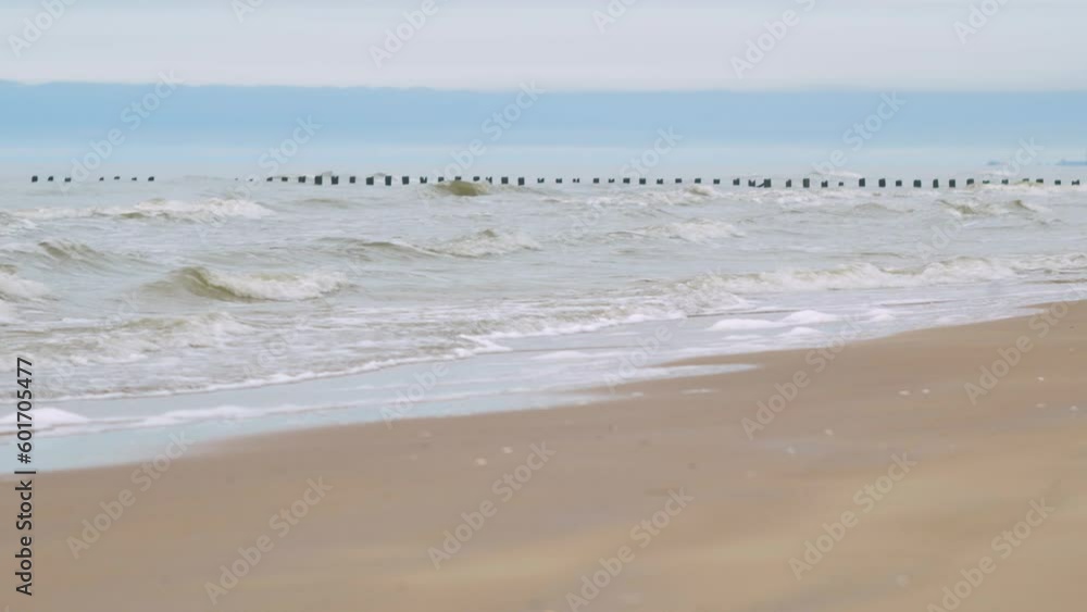 Calm Baltic sea waves breaking against old abandoned wooden pier on the beach, white sand coast, overcast day, wide beautiful shot Calm Baltic sea waves breaking against old abandoned wooden pier on the beach, white sand coast, overcast day, wide beautiful shot