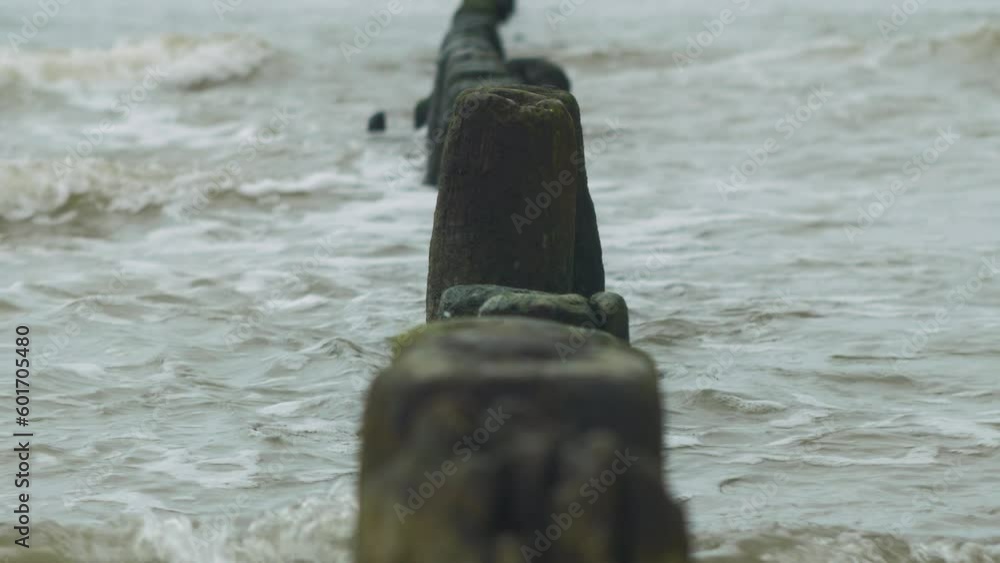Calm Baltic sea waves breaking against old abandoned wooden pier on the beach, white sand coast, overcast day, beautiful medium closeup shot Calm Baltic sea waves breaking against old abandoned wooden pier on the beach, white sand coast, overcast day, beautiful medium closeup shot