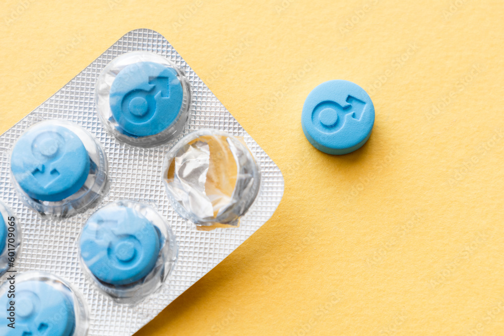 Male gender symbol on blue pills. Blue pills in a blister on a yellow background. Pills for men Male gender symbol on blue pills. Blue pills in a blister on a yellow background. Pills for men