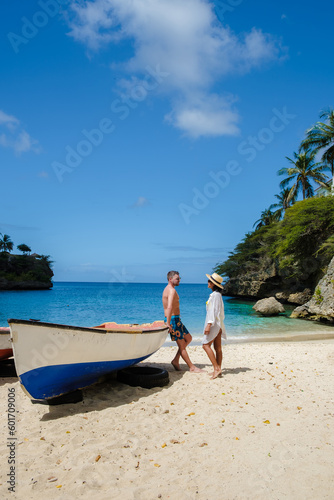 A couple of men and women at the beach of Playa Lagun Beach with a fishing boat at the Island of Curacao, Lagun Beach Curacao a small island in the Caribbean. 
