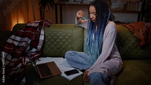 Multitasking young ethnic woman journalist sitting on sofa, recording voice message on mobile phone photo