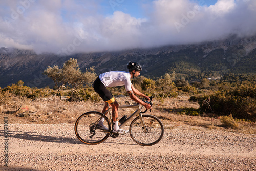 Cyclist practicing on gravel road.Fit male cyclist riding a gravel bike on a gravel road with a view of the mountains, Alicante region of Spain