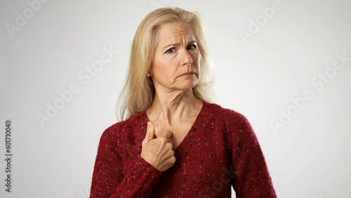 Elderly mature blonde woman lady 50s years old wears red sweater look camera pointing fingers herself ask say who me no thanks i do not need it isolated on solid white background studio portrait photo