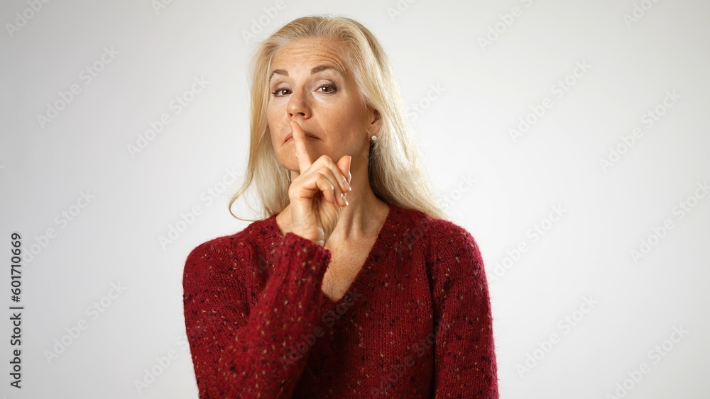 Secret smiling elderly gray-haired blonde woman 50s years old look aside close her mouth lock and throw away key isolated on solid white background studio portrait Secret smiling elderly gray-haired blonde woman 50s years old look aside close her mouth lock and throw away key isolated on solid white background studio portrait