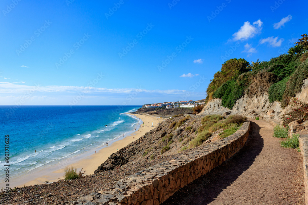 Obraz premium Stunning View of Beach and Sea with Blue Sky from Stone Promenade in Esquinzo, Fuerteventura