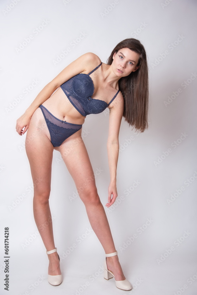 Young woman, brunette. Female model with navy blue bra and underwear. Studio photo with white background.