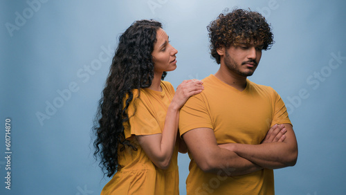 Offended Arabian man Indian husband boyfriend ignoring Latino Hispanic woman wife girlfriend asking forgiveness apologizing after quarrel conflict guilty saying sorry apology at studio blue background photo