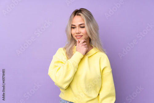 Teenager girl wearing a yellow sweatshirt over isolated purple background looking to the side