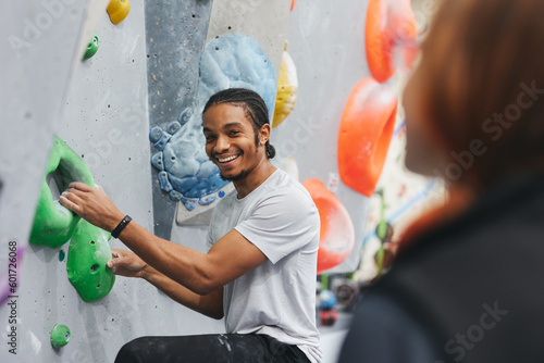 Man On Climbing Wall At Indoor Activity Centre Receiving Personal Lesson From Coach