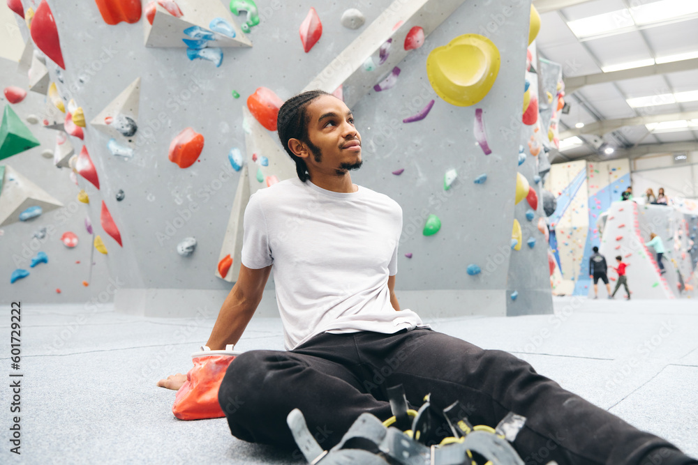 Fototapeta premium Man Sitting on Floor Excited To Try Climbing Wall At Indoor Centre