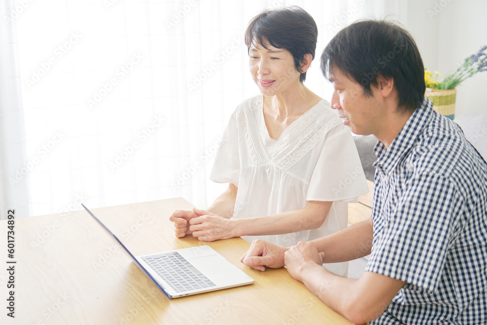 リビングでノートパソコンを見る熟年夫婦 リビングでノートパソコンを見る熟年夫婦