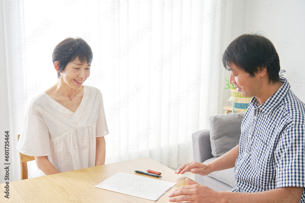熟年結婚 婚姻届を挟んで座る中年男性と中年女性 熟年結婚 婚姻届を挟んで座る中年男性と中年女性