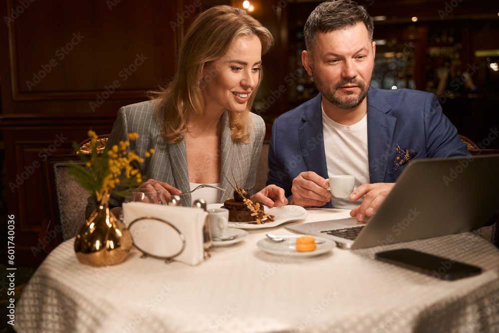 Man and woman enjoying breakfast watching video on laptop Man and woman enjoying breakfast watching video on laptop