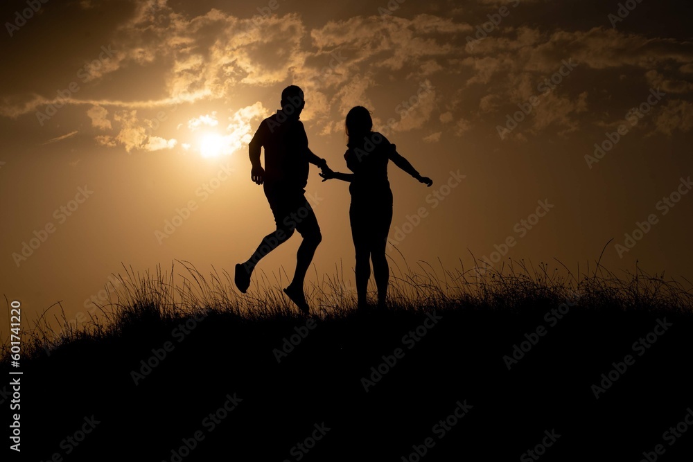 Silhouette of couple jumping against light