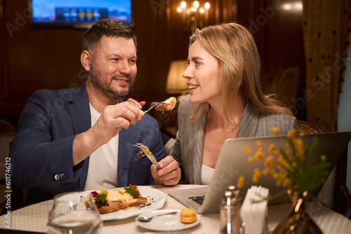 Man treating his girlfriend with tasty dish on date at restaurant