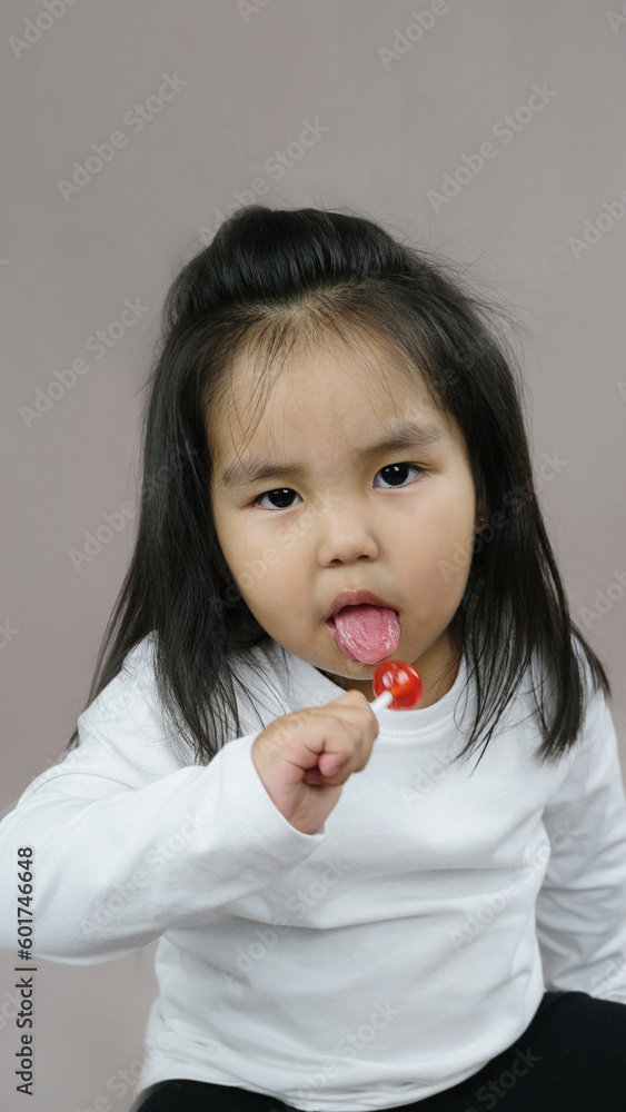Portrait of a little girl holding a lollipop on a stick. The concept of childhood. Portrait of a little girl holding a lollipop on a stick. The concept of childhood.