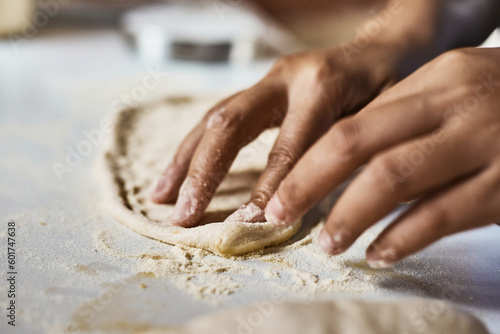 Hands knead dough to make a pizza