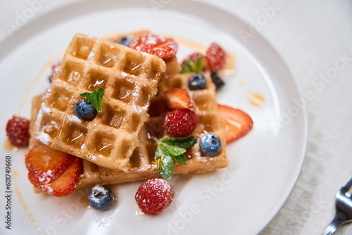 Close-up delicious crunchy waffles with berries and honey