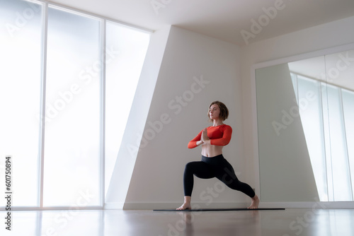 Beautiful Caucasian woman doing physical exercise and meditation by doing yoga in gym.