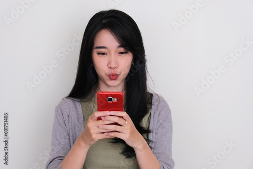 Closeup portrait of Asian young women showing funny face expression when texting on handphone photo