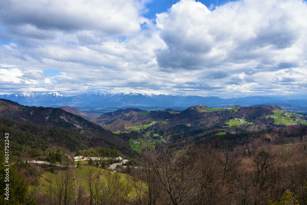 View of Kamnik–Savinja Alps and Polhov Gradec Hills covered in meadow and forest in Gorenjska, Slovenia with stratocumulus clouds in the sky