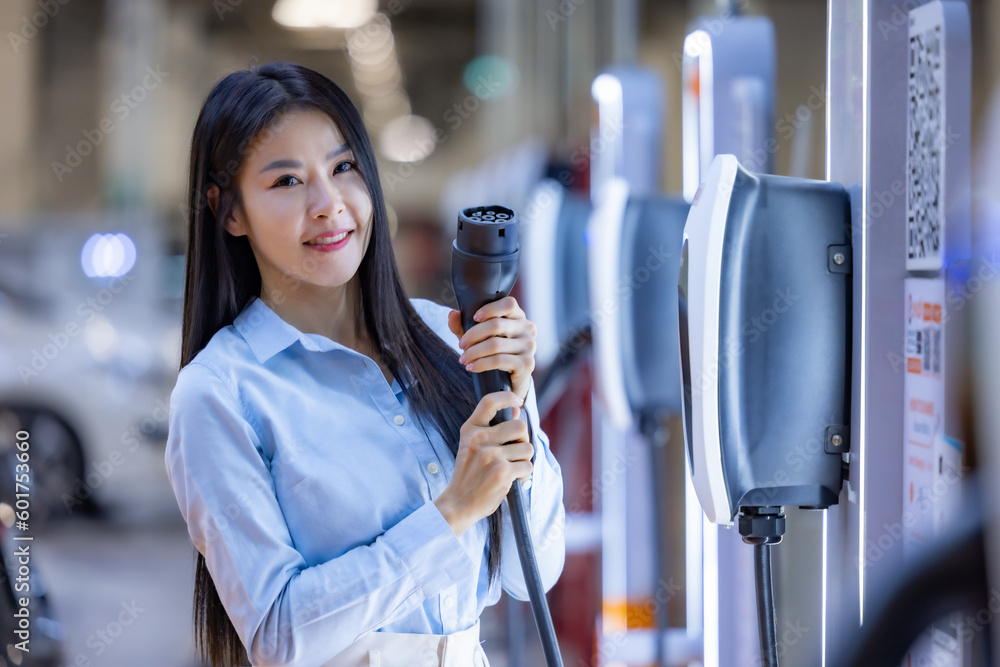 Young Asian woman holding the CCS 2 EV charging connector at EV ...