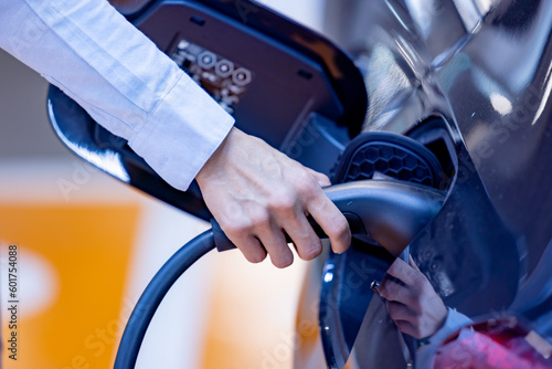 Woman holding the CCS 2 EV charging connector at EV charging station in department store. EV-electric vehicle charging connector for a vehicle. EV charging an electric car. Nature energy,Clean energy.