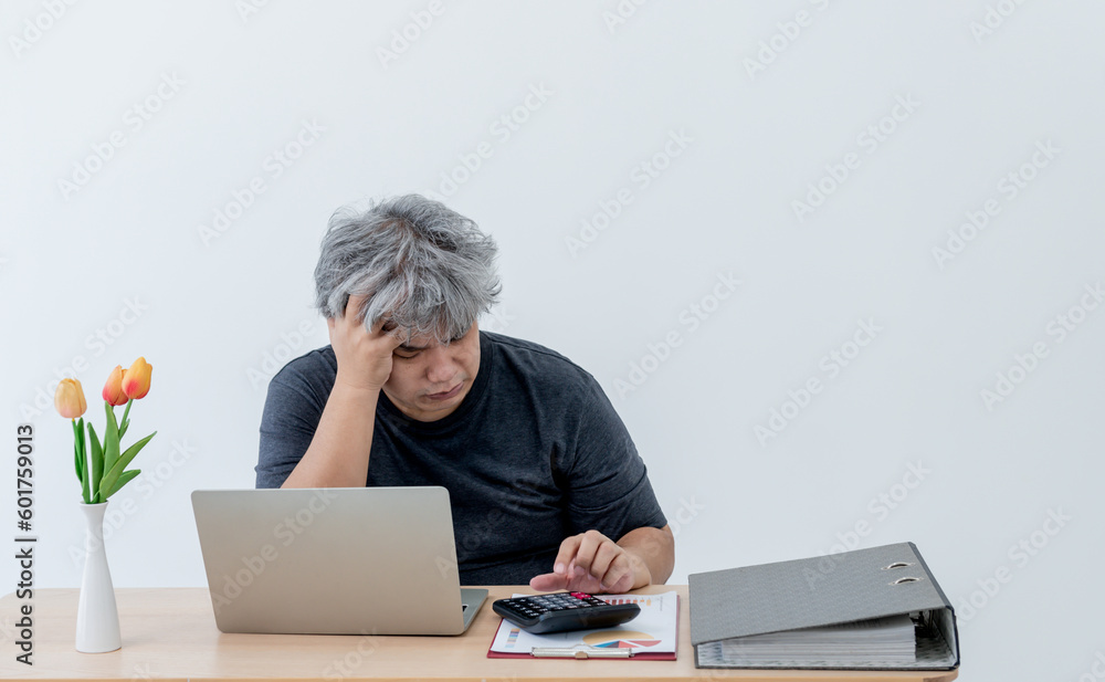 Asian business men Feeling stressed While he using a calculator calculate for unsuccessful earning, at workplace, with white background to people and business loss concept. Asian business men Feeling stressed While he using a calculator calculate for unsuccessful earning, at workplace, with white background to people and business loss concept.