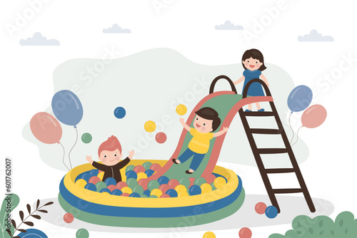 Little kids slide down slide into pool and plays with plastic balls. Children party in entertaining playroom. Colored play balls for small children. Childhood, education and imagination.