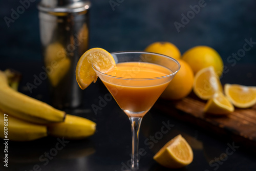 cocktail glass with orange juice shaker and natural oranges and bananas and splash with liquid flying in the air