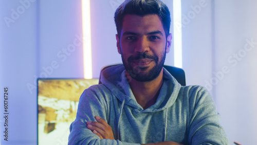 Portrait of Middle East man Gamer put off headset turn around looking at camera. Young male stop using headphone crossing arm after play Online game live stream on Computer in Neon Light room