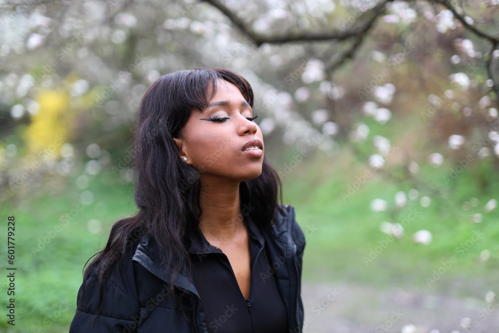 African woman enjoys the scent of spring flowers in the park. African woman enjoys the scent of spring flowers in the park.