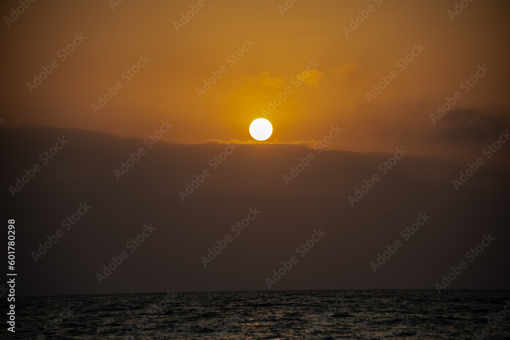 orange sunset over the see with a little fog and dramatic sun