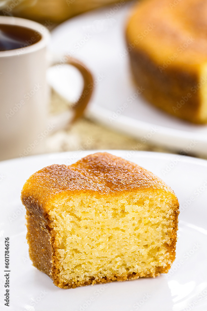 small slice of cornmeal cake, typical Brazilian rural cake made with corn flour, with hot coffee in the background, Brazilian breakfast small slice of cornmeal cake, typical Brazilian rural cake made with corn flour, with hot coffee in the background, Brazilian breakfast