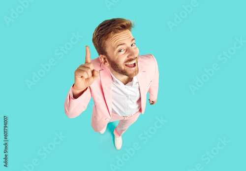 Konstfotografi Funny young man in trendy pink suit standing isolated on blue background has good, clever, genius idea, looks at camera with happy face expression, and points his forefinger up