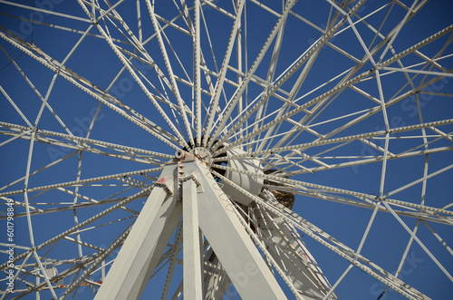 View of the steel structure of a fairground ferris wheel  with the axis  the spokes and the blue sky in the background