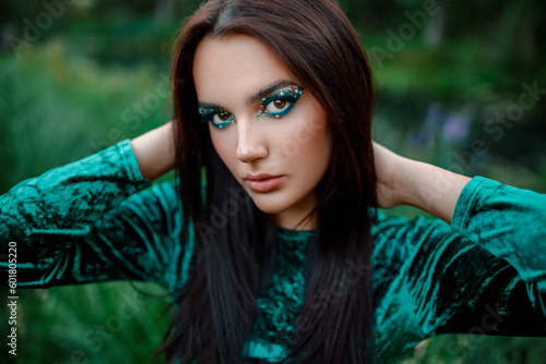 Girl with beautiful makeup on a background of green foliage