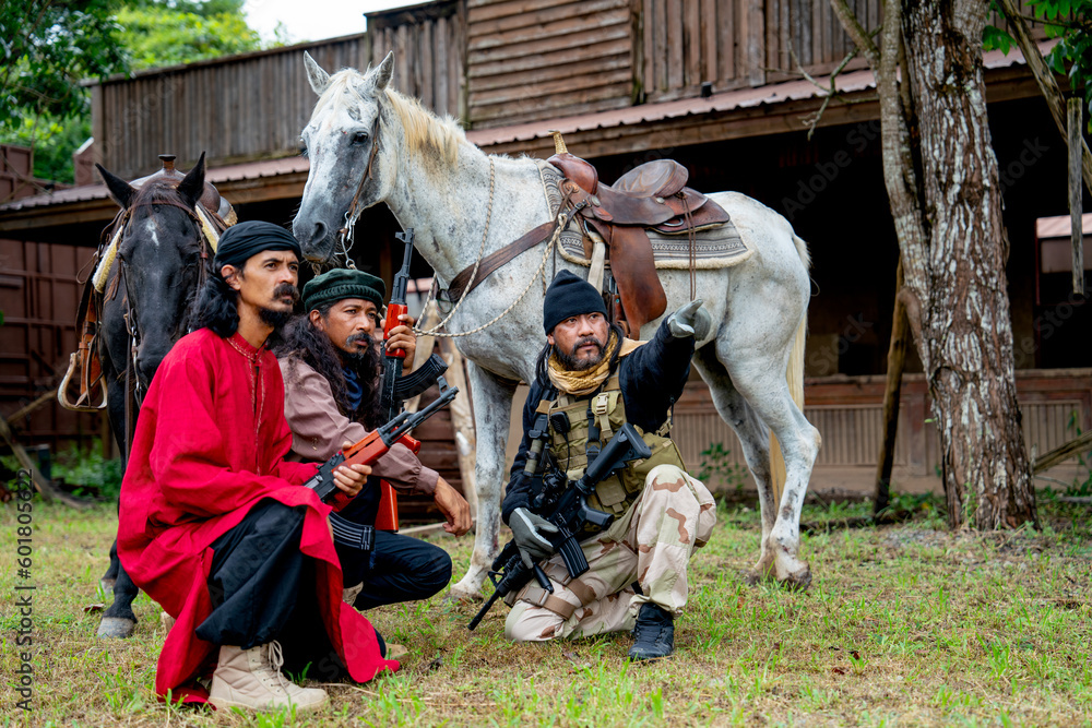 Group of men with soldier and arab clothes sit down in front of horse and old building look like discuss plan to fighting with enemy. Group of men with soldier and arab clothes sit down in front of horse and old building look like discuss plan to fighting with enemy.
